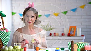 Beautiful woman in cute headband holding dyed eggs, tutorial for Easter crafts photo