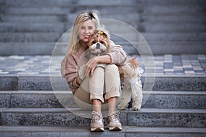 Beautiful woman with a cute pet dog, Shih Tzu. Sitting in a stone staircase. Lifestyle