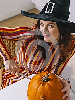 Beautiful woman cutting a pumpkin for Halloween