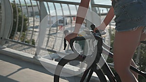 Beautiful woman cyclist rides bike along beach boardwalk in the morning with sea on background. Female bike rider in stylish casua