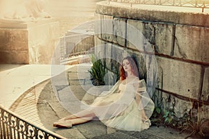 Beautiful woman dancer resting in the shade of a stone building.