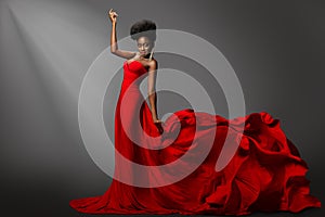 Beautiful Woman dancing in Red waving Dress on Stage. Fashion Dark Skin Model in long Gown Side View. Stylish Girl with Afro hair