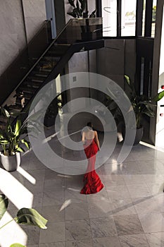 beautiful woman with dark hai in elegant red dress posing in luxury hotel hall