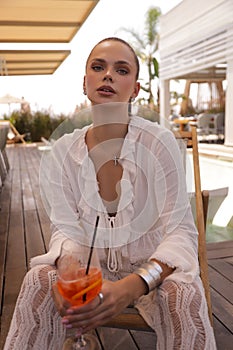 beautiful woman with dark hair in elegant clothes and accessories relaxing in summer beach club