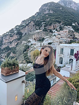 beautiful woman with dark hair in elegant clothes posing against the backdrop of the city Positano in Italy