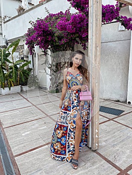 beautiful woman with dark hair in elegant clothes posing against the backdrop of the city Positano in Italy