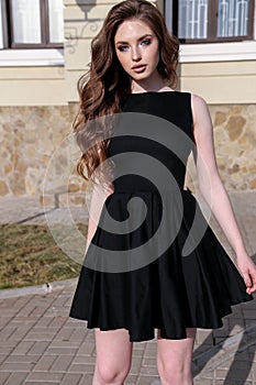Beautiful woman with dark hair in elegant dress walking on the s