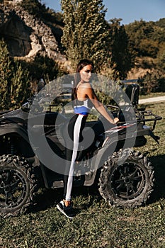 Beautiful woman with dark hair in elegant sportive suit posing in quad bike