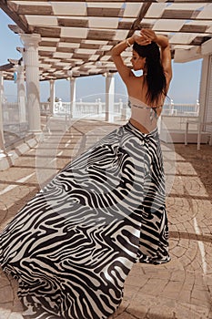 beautiful woman with dark hair in elegnt dress with zebra print posing in beach club