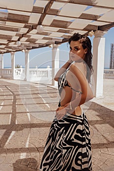 beautiful woman with dark hair in elegnt dress with zebra print posing in beach club