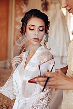 Beautiful woman with dark hair posing in silk robe in the morning of her wedding day