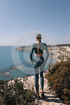 beautiful woman with dark hair in sportive suit posing on a hill overlooking the beach Kourion in Cyprus