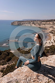 beautiful woman with dark hair in sportive suit posing on a hill overlooking the beach Kourion in Cyprus