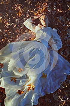 Beautiful woman daydreaming on a bed of leaves photo