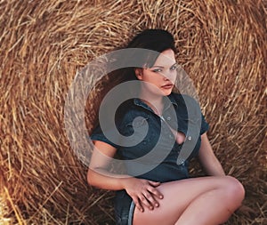 Beautiful woman in denim suit near haystack, soft focus