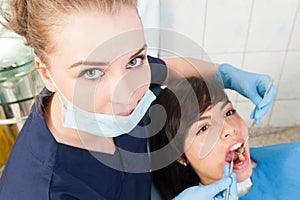 Beautiful woman dentist examining female patient teeth