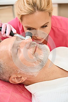 Beautiful woman dermatologist conducts an examination using a dermatoscope