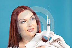 Beautiful woman doctor cosmetologist holding syringe with solution for beauty injections. isolated female studio portrait