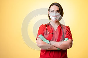 Beautiful woman doctor with stethoscope, wearing red scrubs with protective mask looking confidence