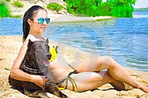 Beautiful woman and dog sitting on the beach