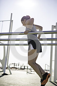 Beautiful woman doing dips on bar at outdoor training spot or street workout in Barcelona beach & x28;SPAIN