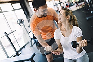 Beautiful woman doing exercises in gym with personal trainer