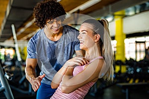 Beautiful woman doing exercises in gym with personal trainer together. Sport, people concept