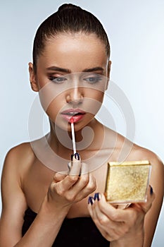 Beautiful Woman Doing Makeup Putting Lipgloss On Lips. Cosmetics
