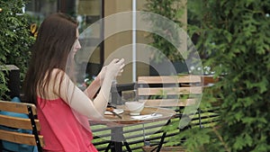 Beautiful woman doing selfie, sitting in summer cafe outdoors.
