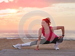 Beautiful woman doing yoga fitness exercise in sport clothes on a wooden pier. Sea and sunset sky background.