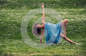 Beautiful woman doing yoga on meadow