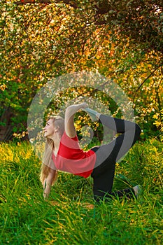 Beautiful woman doing yoga outdoors On green grass