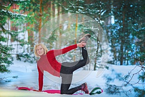 Beautiful woman doing yoga outdoors in the snow