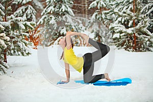Beautiful woman doing yoga outdoors in the snow