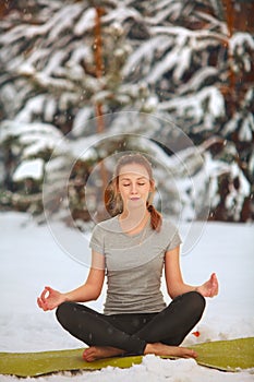 Beautiful woman doing yoga outdoors in snow