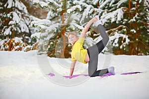 Beautiful woman doing yoga outdoors in the snow photo