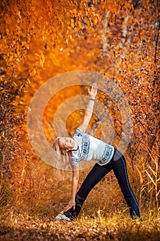 Beautiful woman doing yoga outdoors On yellow grass