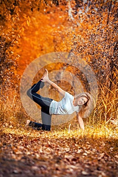 Beautiful woman doing yoga outdoors On yellow leaves