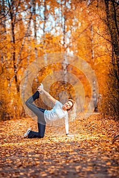 Beautiful woman doing yoga outdoors On yellow leaves