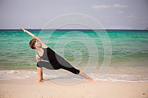 Beautiful woman doing yoga on the sea