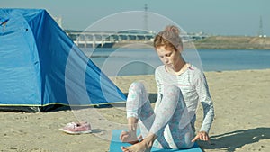 Beautiful woman doing yoga at sea, harmony and freedom, background from sea and sand blue tourist tent, concept of yoga