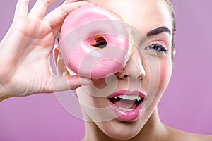 Beautiful woman with donuts, one eye than have a pink donut photo