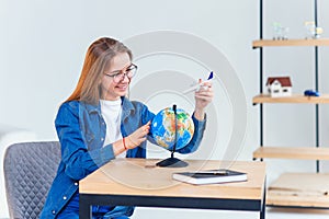 Beautiful woman dreaming about vacation. Girl holds in hand a model of airplane and flies around small globe.