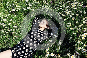 beautiful woman in a dress with flowers lies in the grass with daisies