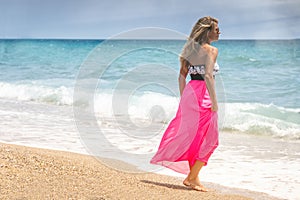 Beautiful woman in a dress walking on the beach.Relaxed woman breathing fresh air,emotional sensual woman near the sea, enjoying s