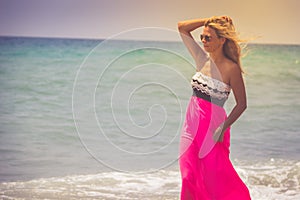 Beautiful woman in a dress walking on the beach.Relaxed woman breathing fresh air,emotional sensual woman near the sea, enjoying s