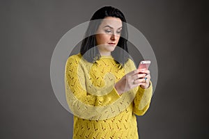 Beautiful woman dressed casually looks surprised at the phone