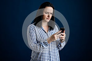 Beautiful woman dressed casually thinks of the message and looks surprised at the phone