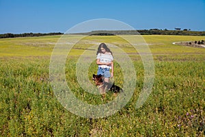 Beautiful woman dresss German Shepherd on a walk in a field