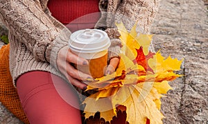 Beautiful woman drinking coffee in autumn park. Woman holding cup of coffee in the hands outdoor